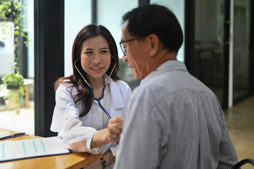 A clinician listening to an adult’s chest with a stethoscope